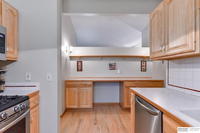 kitchen with appliances with stainless steel finishes, light hardwood / wood-style floors, built in desk, and light brown cabinets