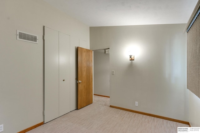 unfurnished bedroom with a closet, light colored carpet, and lofted ceiling