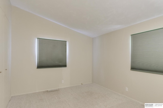 carpeted spare room featuring lofted ceiling