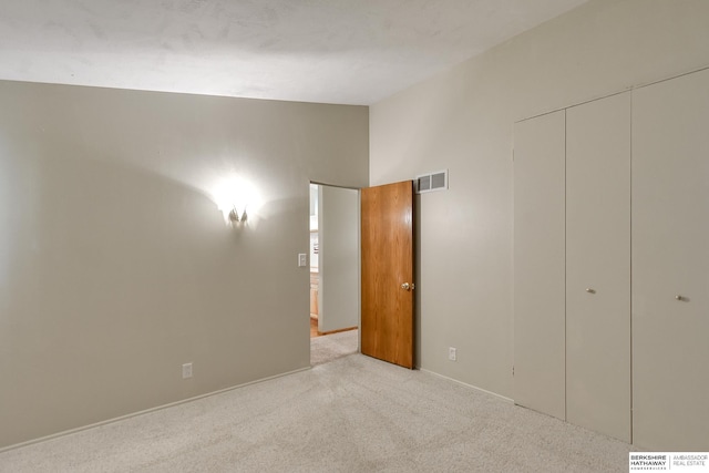 unfurnished bedroom featuring light carpet, vaulted ceiling, and a closet