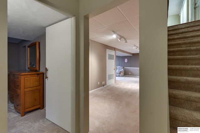 hallway with rail lighting and light colored carpet