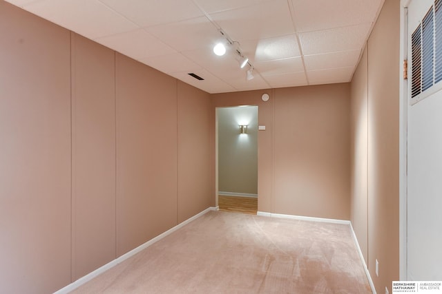 carpeted spare room with a paneled ceiling and rail lighting