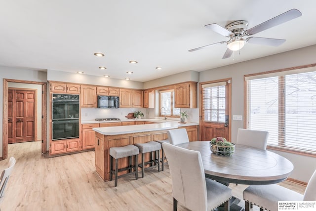 dining area with ceiling fan, light hardwood / wood-style flooring, and sink