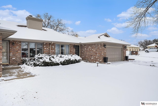 snow covered back of property featuring a garage