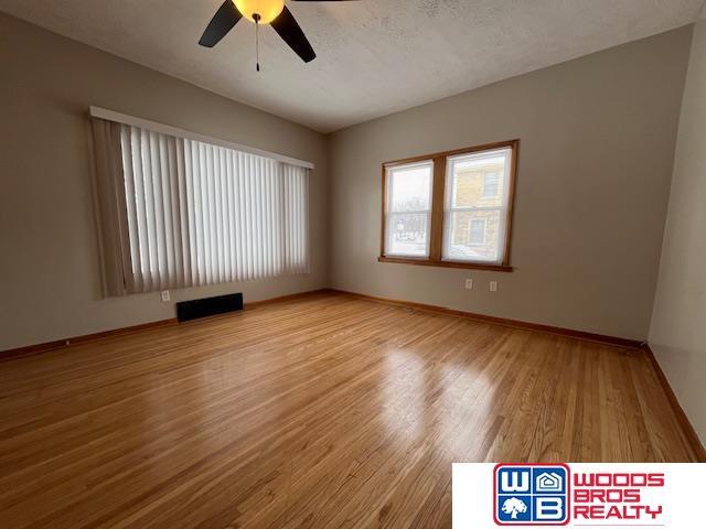 spare room featuring a textured ceiling, ceiling fan, and light hardwood / wood-style flooring