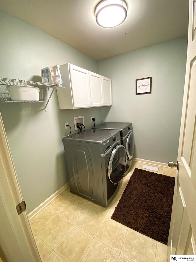 clothes washing area featuring light tile patterned floors, washer and clothes dryer, and cabinets