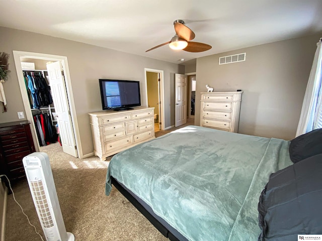 bedroom with a closet, ceiling fan, a spacious closet, and carpet floors