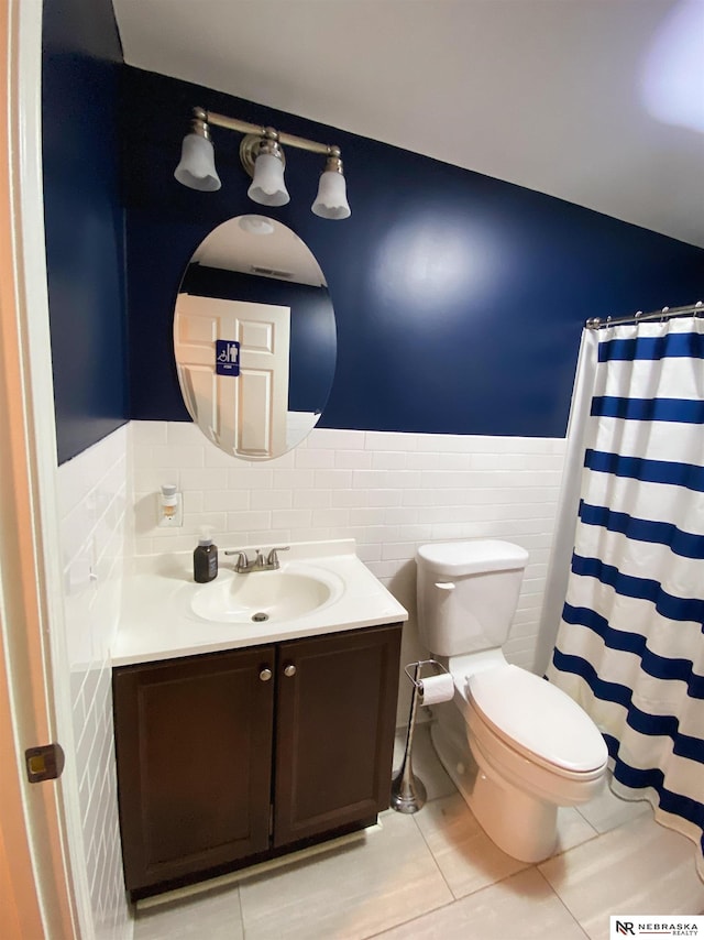 bathroom with tile walls, toilet, vanity, and tile patterned flooring