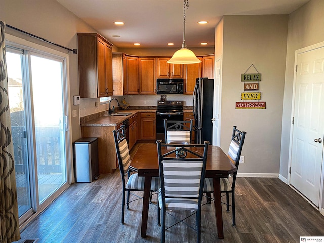 kitchen featuring decorative light fixtures, sink, dark hardwood / wood-style floors, and black appliances