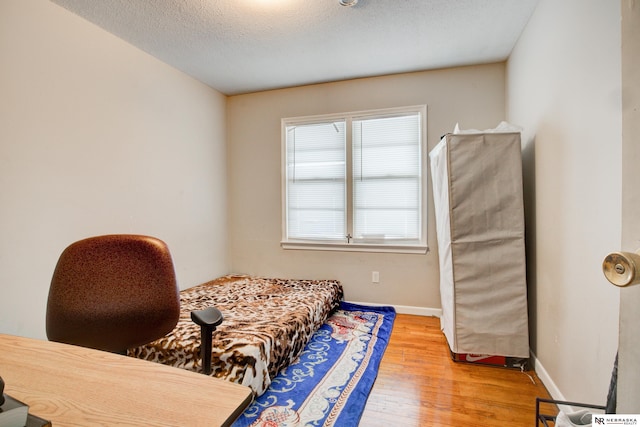 bedroom with a textured ceiling and hardwood / wood-style flooring