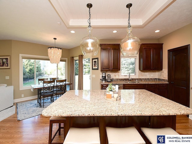 kitchen featuring a tray ceiling, sink, and a center island