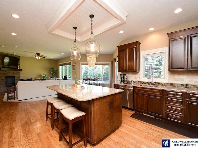 kitchen featuring decorative light fixtures, a kitchen island, sink, a tray ceiling, and dishwasher