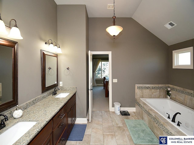 bathroom with vaulted ceiling, a wealth of natural light, vanity, and a relaxing tiled tub