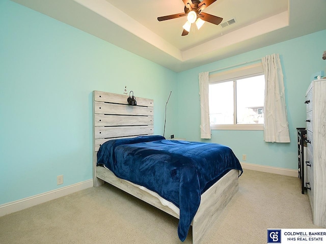 carpeted bedroom featuring a tray ceiling and ceiling fan