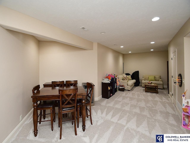 carpeted dining space with a textured ceiling