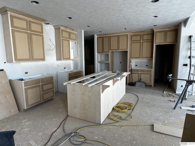 kitchen with light brown cabinets, a kitchen island, and a textured ceiling