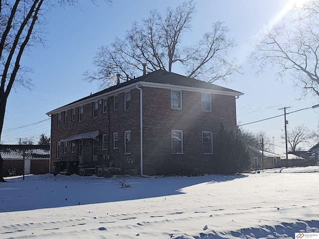 snow covered property featuring brick siding