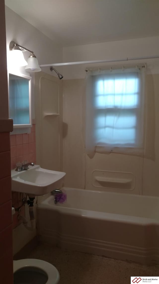 bathroom with toilet, tub / shower combination, speckled floor, and a sink