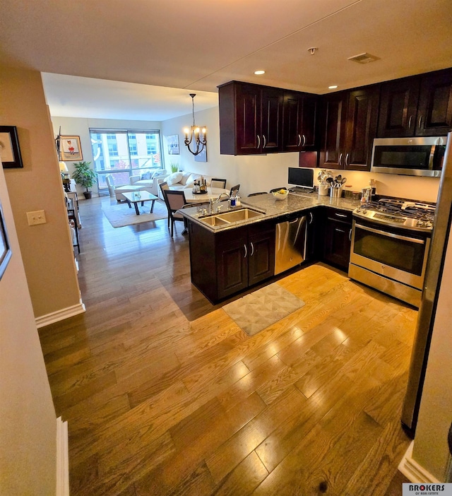 kitchen with light wood-type flooring, pendant lighting, stainless steel appliances, and sink