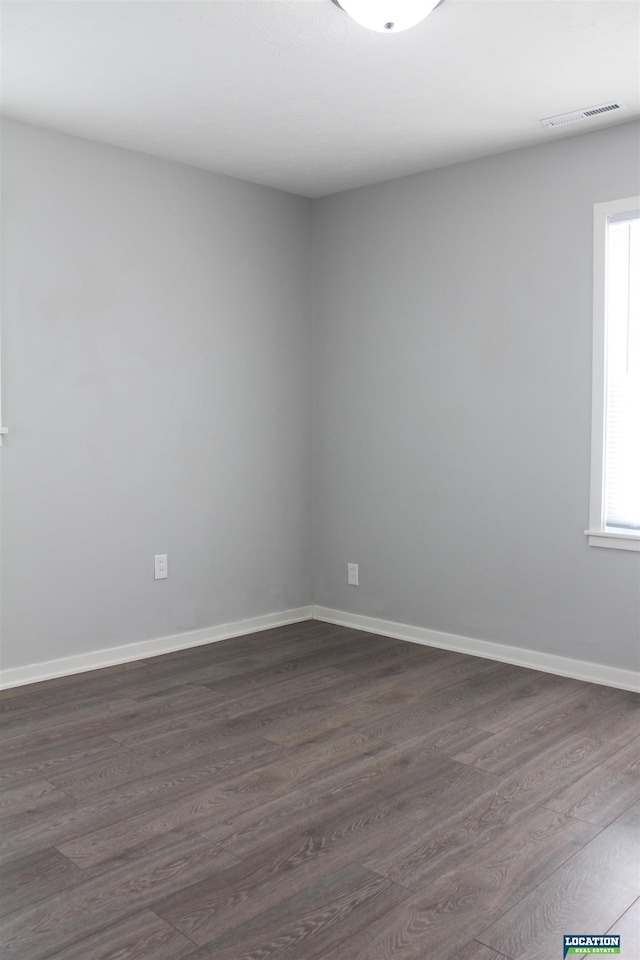 spare room featuring dark wood-style floors, baseboards, and visible vents