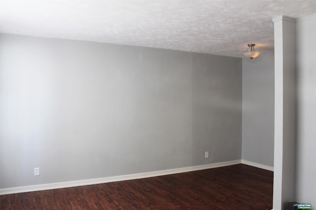 spare room featuring a textured ceiling, baseboards, and dark wood-type flooring