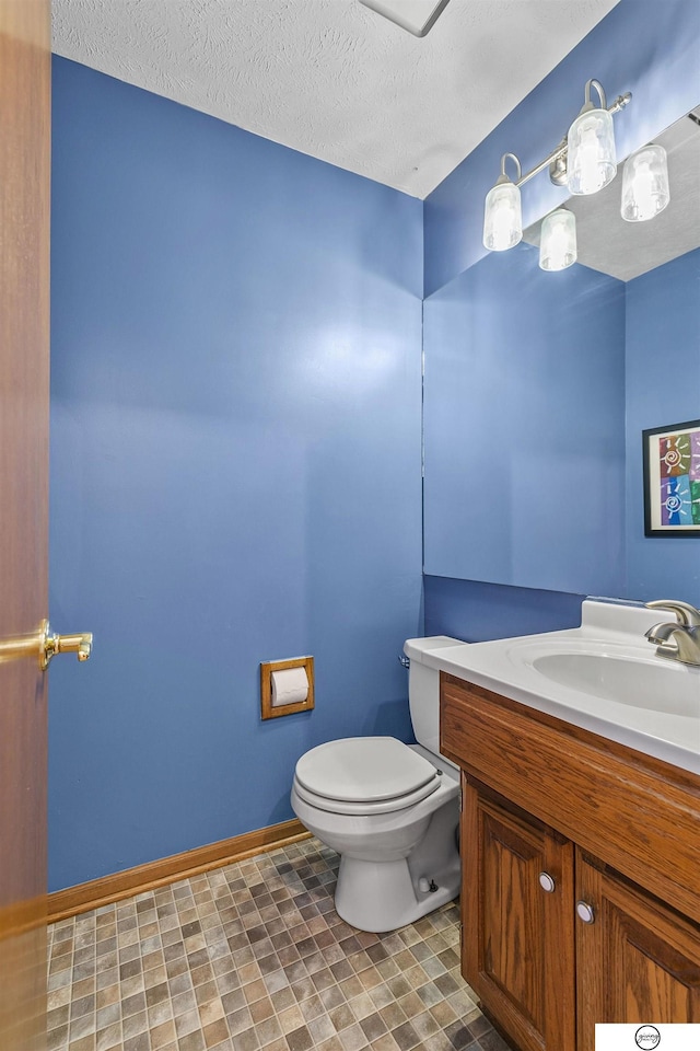 bathroom with a textured ceiling, vanity, and toilet