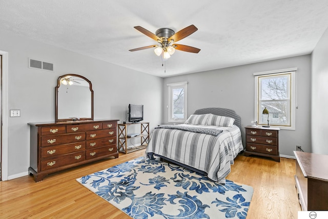 bedroom with multiple windows, a textured ceiling, and light hardwood / wood-style floors