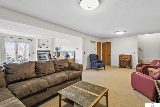 carpeted living room featuring a textured ceiling and built in features