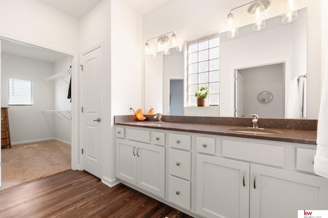 full bathroom featuring double vanity, wood finished floors, a sink, and baseboards