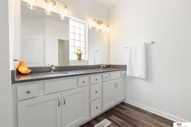 full bathroom with double vanity, baseboards, visible vents, wood finished floors, and a sink