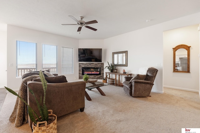 living room featuring carpet, a fireplace, baseboards, and a ceiling fan