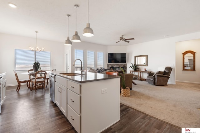 kitchen featuring white cabinets, dark wood-type flooring, a fireplace, a sink, and ceiling fan with notable chandelier