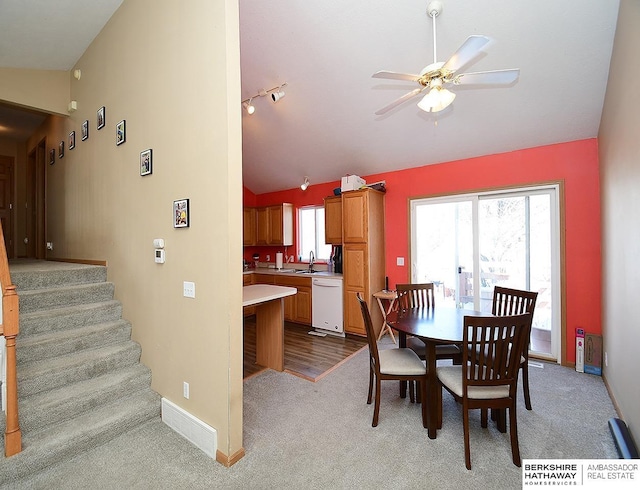 carpeted dining space with sink, track lighting, vaulted ceiling, and ceiling fan