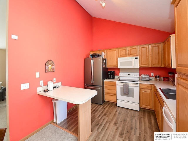 kitchen featuring lofted ceiling, sink, light hardwood / wood-style flooring, and white appliances