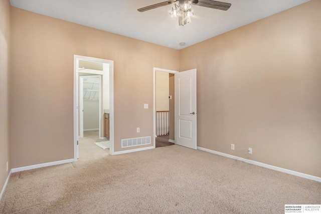 unfurnished bedroom featuring a closet, light carpet, a walk in closet, and ceiling fan