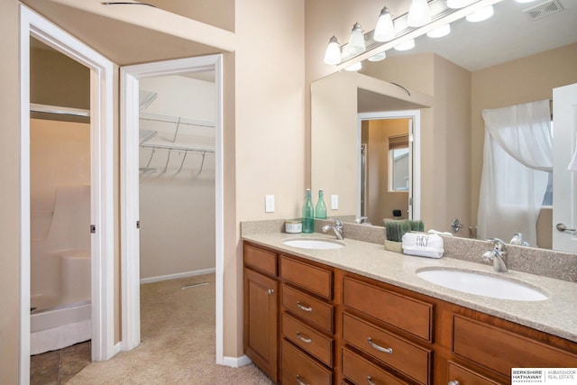 full bath with a sink, visible vents, a spacious closet, and double vanity