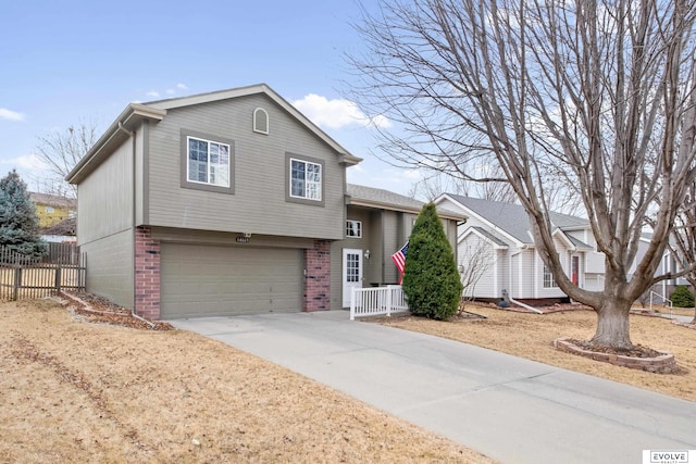 split level home featuring brick siding, fence, driveway, and a garage