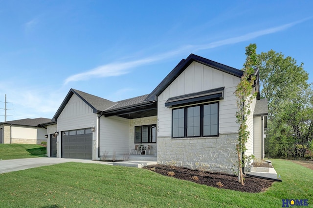 modern farmhouse style home with stone siding, a garage, concrete driveway, board and batten siding, and a front yard