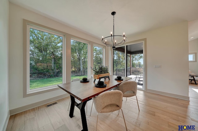 dining space with baseboards, visible vents, light wood finished floors, and a notable chandelier