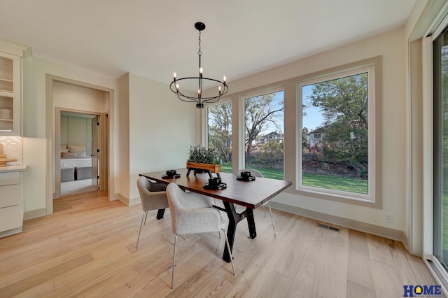 dining space with baseboards, an inviting chandelier, visible vents, and light wood-style floors