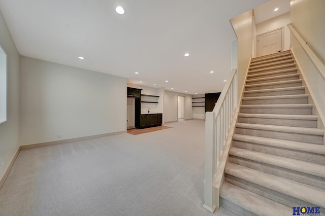 interior space with light colored carpet, baseboards, recessed lighting, and stairway