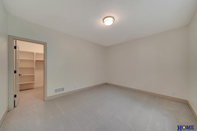 unfurnished bedroom with light carpet, baseboards, visible vents, a spacious closet, and a closet