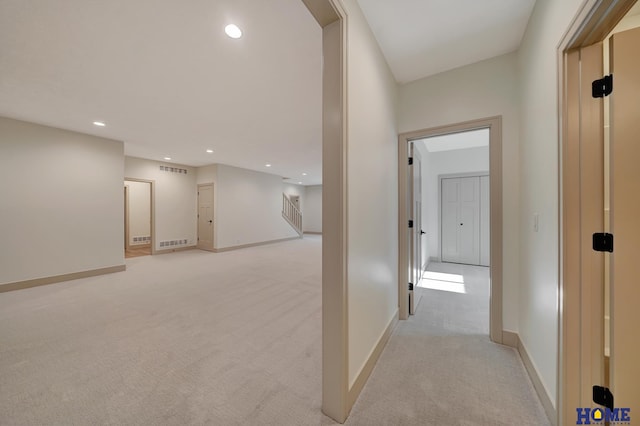 hall featuring baseboards, visible vents, recessed lighting, and light carpet