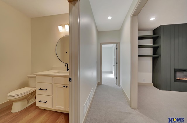 bathroom featuring baseboards, vanity, a large fireplace, and toilet