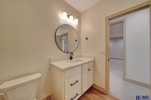 bathroom with baseboards, vanity, toilet, and wood finished floors