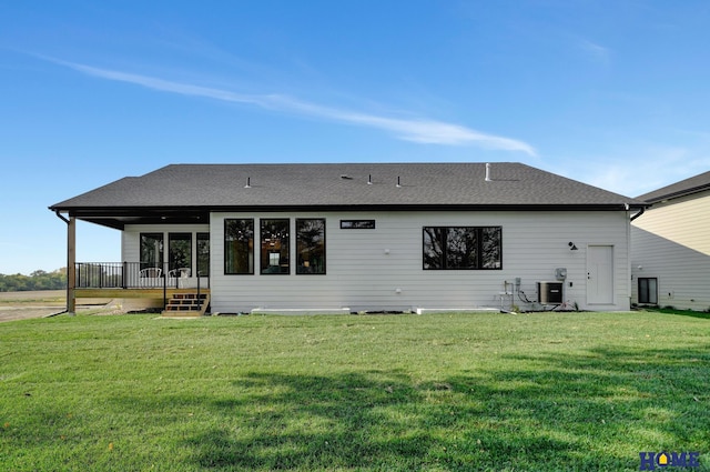 rear view of house with central AC, a shingled roof, and a yard