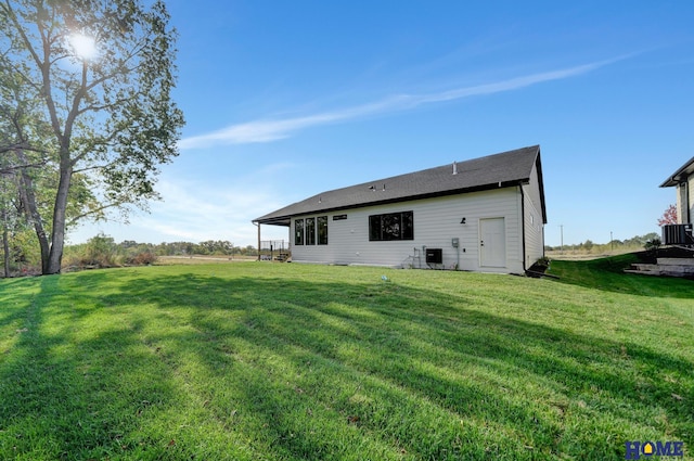 back of house with central AC and a lawn