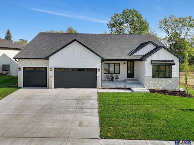 modern farmhouse with stone siding, driveway, a garage, board and batten siding, and a front yard