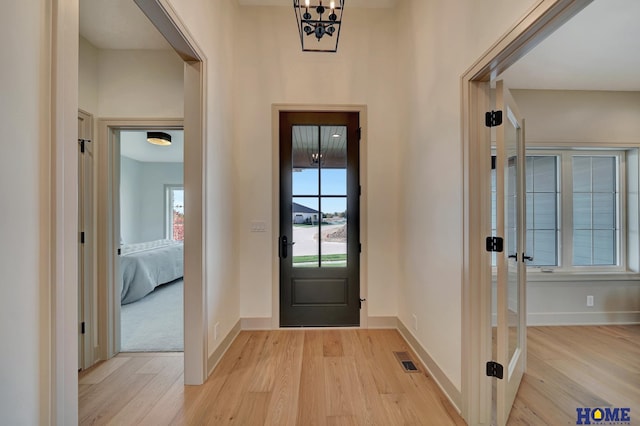 entrance foyer with light wood-style flooring, visible vents, baseboards, and a healthy amount of sunlight