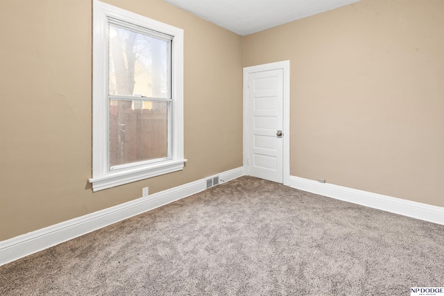 spare room featuring carpet flooring, baseboards, and visible vents